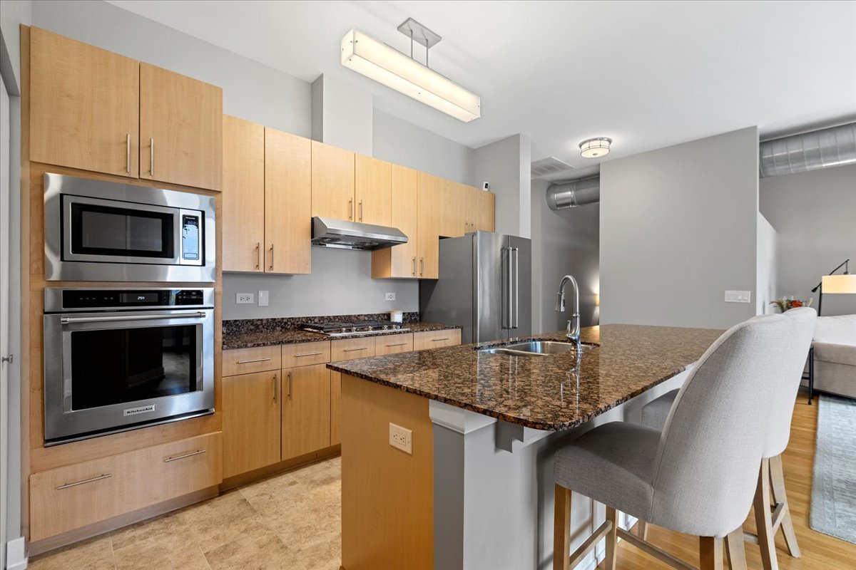 1155 West Madison Street, Unit 603 Chicago, IL 60607 - Photo 7 of 23 a kitchen with kitchen island a counter space a sink appliances and cabinets