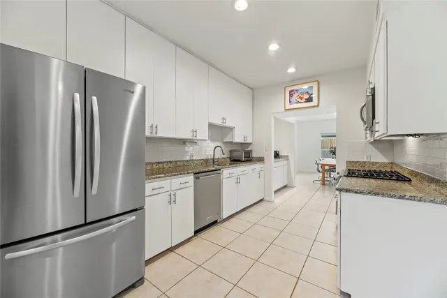 a kitchen with white cabinets a sink and appliances