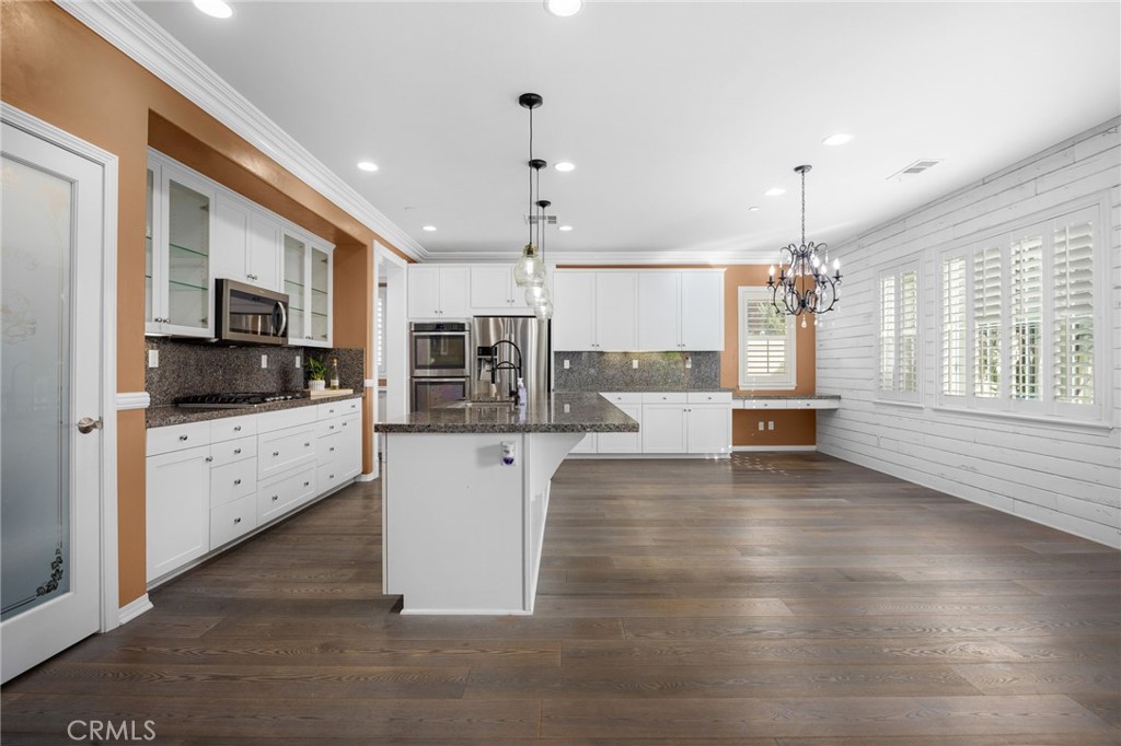 31639 Country View Road Temecula, CA 92591 - Photo 12 of 75 a kitchen with stainless steel appliances kitchen island granite countertop a stove top oven a sink a refrigerator with white cabinets and wooden floor