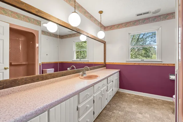 a bathroom with a granite countertop double vanity sink a mirror and a bathtub