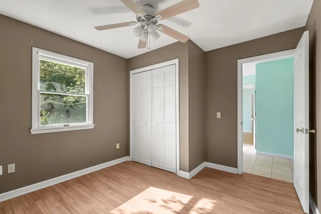 a view of an empty room with window and wooden floor