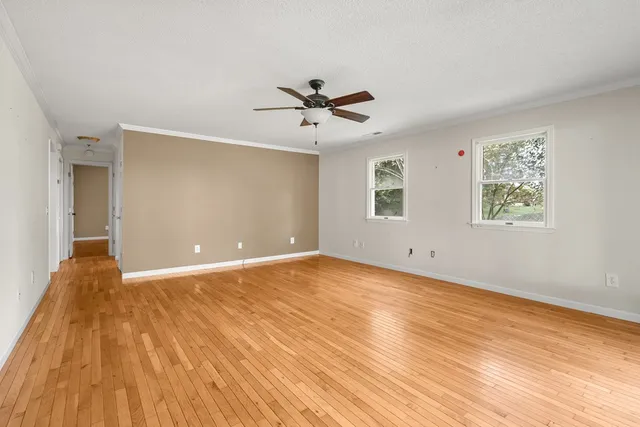 an empty room with wooden floor and windows