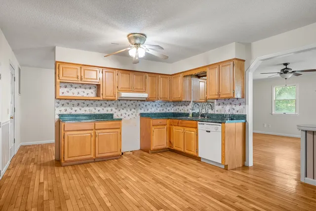 a kitchen with granite countertop wooden cabinets a sink and dishwasher with wooden floor