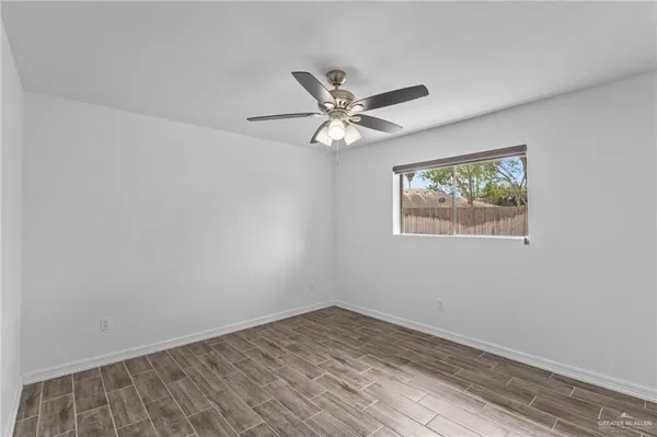 an empty room with wooden floor and ceiling fan