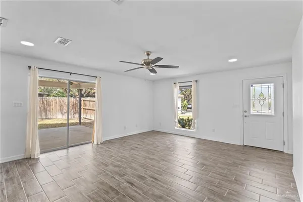 an empty room with wooden floor and windows