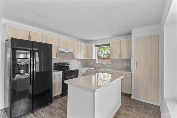 a kitchen with a refrigerator sink and cabinets