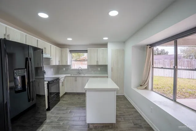 a kitchen with a refrigerator sink and cabinets