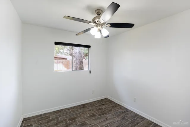 an empty room with wooden floor fan and windows