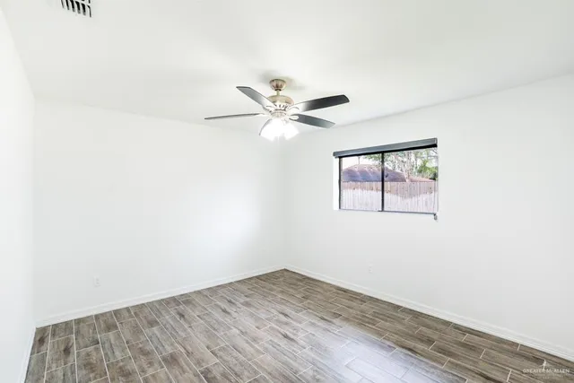 an empty room with wooden floor and ceiling fan