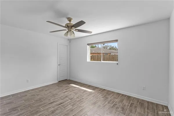 a view of empty room with wooden floor and fan