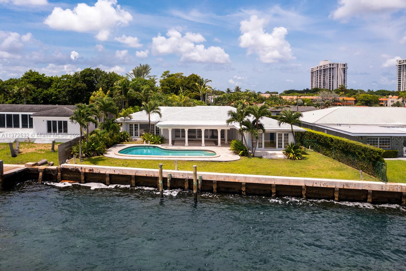 1690 Northeast 104th Street Miami Shores, FL 33138 - Photo 1 of 36 a view of a swimming pool with lawn chairs under an umbrella