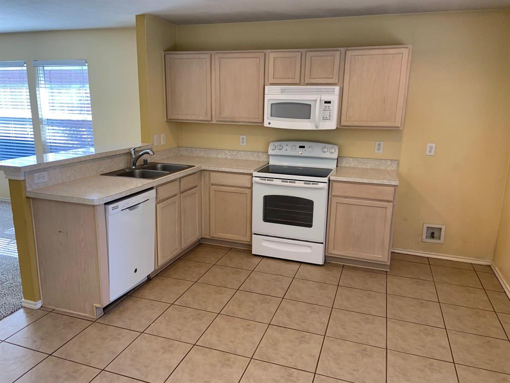 2620 Caprock Road McKinney, TX 75071 - Photo 15 of 19 Kitchen with white appliances, a peninsula, light countertops, light wood finish cabinets, and light tile patterned floors