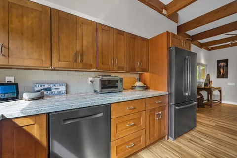 a kitchen with granite countertop wooden cabinets stainless steel appliances a sink and a counter space