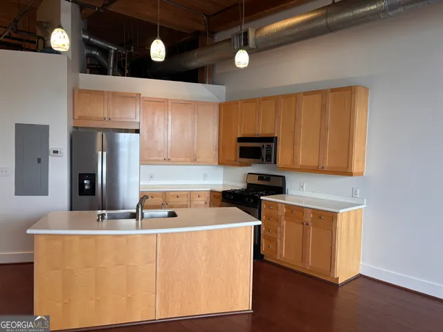 a kitchen with stainless steel appliances a stove a refrigerator a sink cabinets and wooden floor