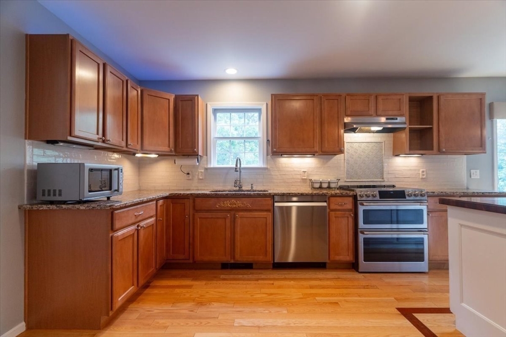 82 Hammersmith Drive Saugus, MA 01906 - Photo 11 of 42 a kitchen with granite countertop a stove top oven sink and cabinets