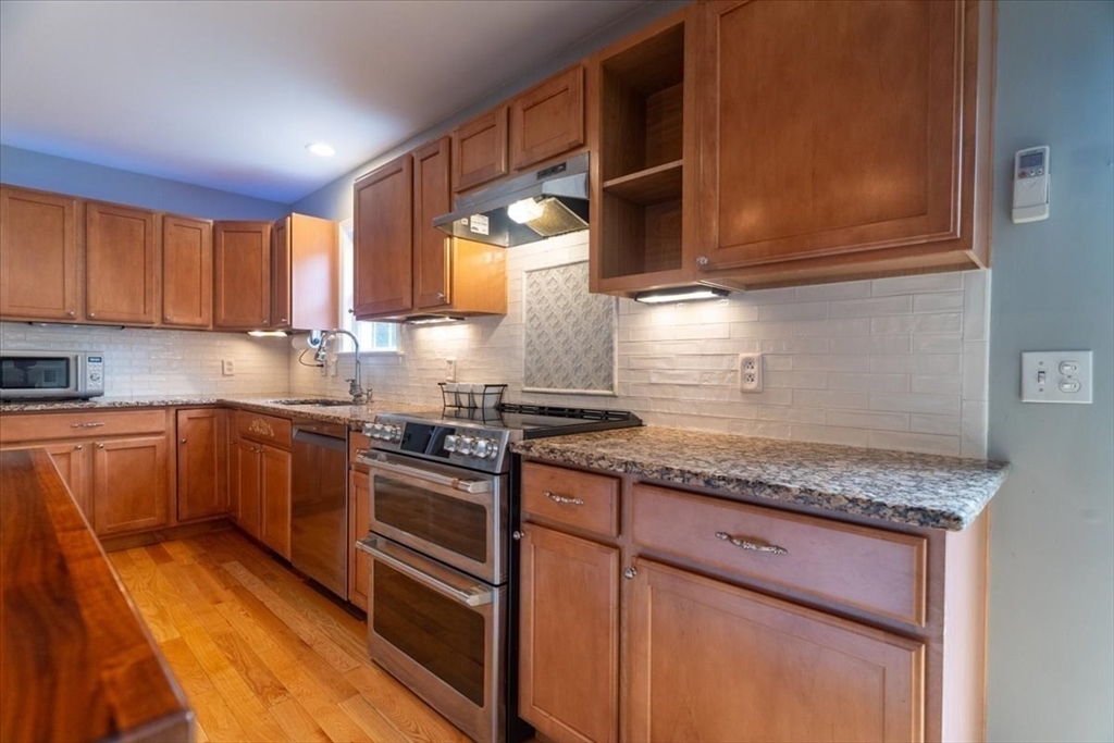 82 Hammersmith Drive Saugus, MA 01906 - Photo 10 of 42 a kitchen with granite countertop wooden cabinets stainless steel appliances and a counter space