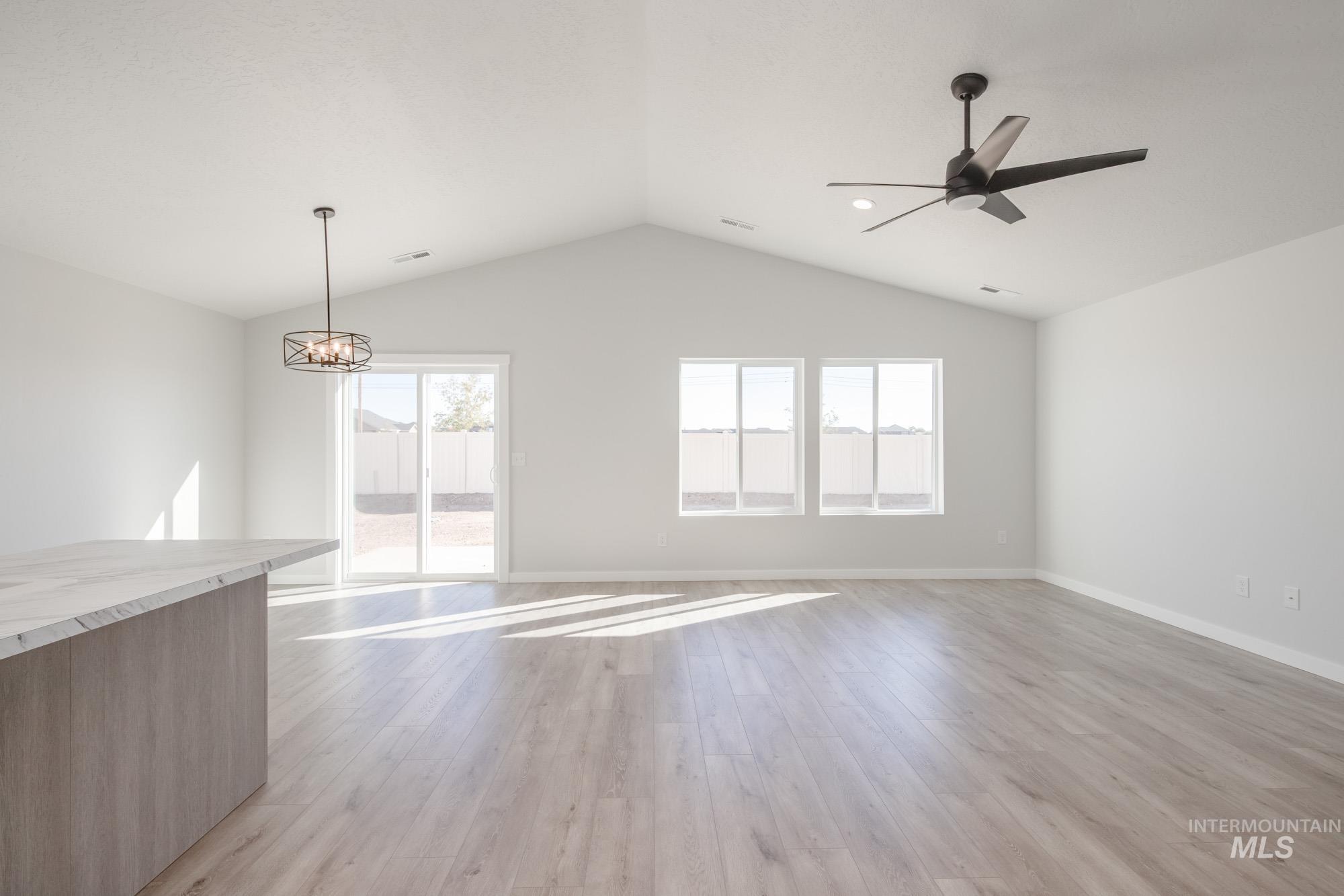 14092 Shiny Spruce Street Caldwell, ID 83607 - Photo 11 of 22 Open-concept living space featuring vaulted ceilings, wood-finish flooring, and multiple windows