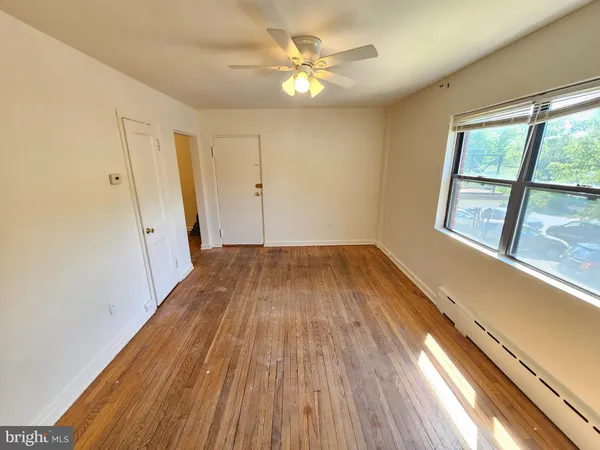 a view of empty room with wooden floor and fan