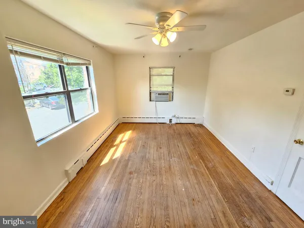 a view of empty room with wooden floor and fan