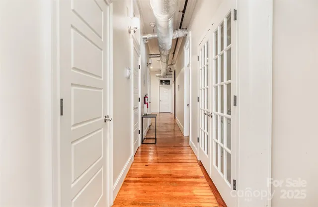 a view of a hallway with wooden floor and staircase