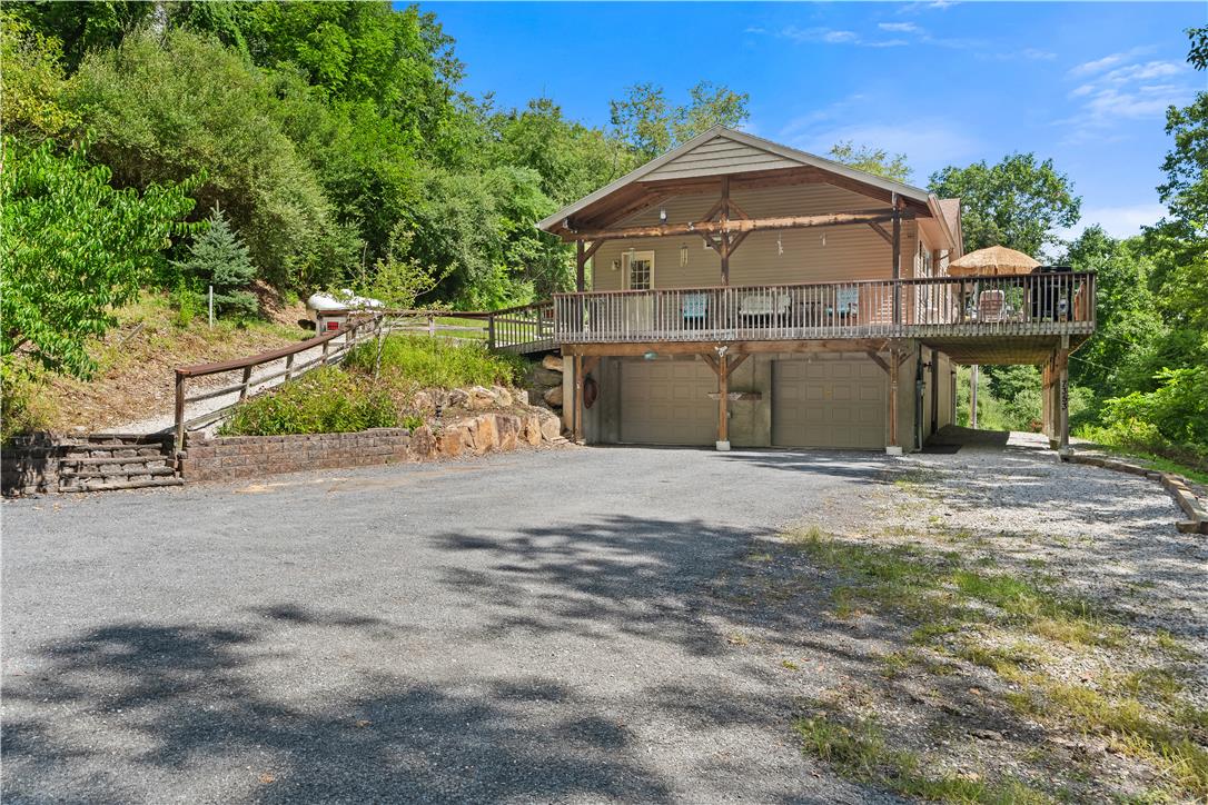 7353 Farrier Road Orefield, PA 18069 - Photo 10 of 74 Nestled against a lush wooded hillside, a raised exterior features a large deck over garage spaces.