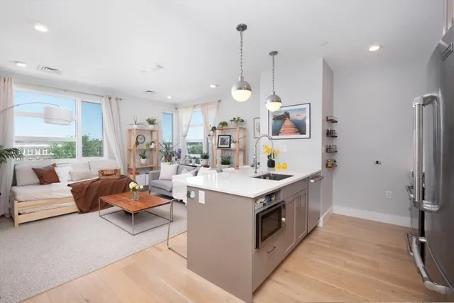 a large kitchen with kitchen island a large counter space a sink appliances and living room view