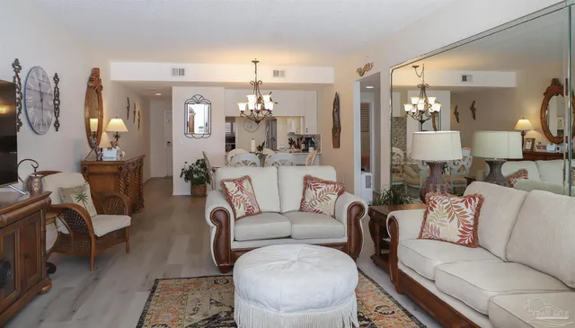 a dining room with wooden floor a chandelier a wooden table and chairs