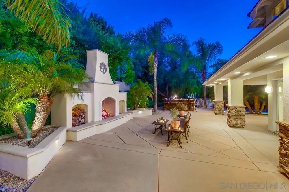 16052 Country Day Road Poway, CA 92064 - Photo 11 of 75 a view of a patio with dining table and chairs with a fire pit and large trees