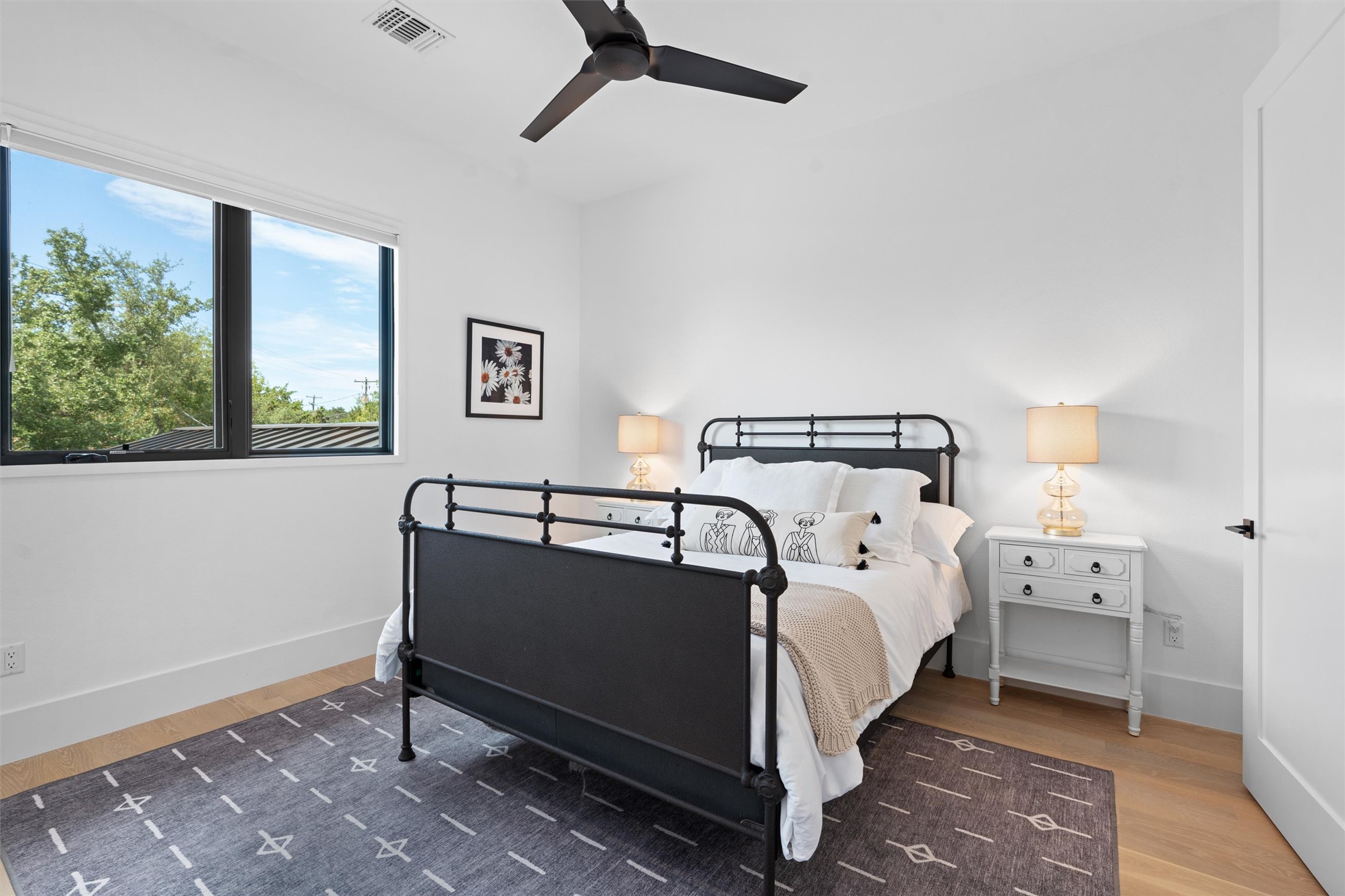 1500 The High Road Austin, TX 78746 - Photo 26 of 40 Light-filled room featuring a large window, a modern ceiling fan, wood-finish flooring, white baseboards, and a white interior door