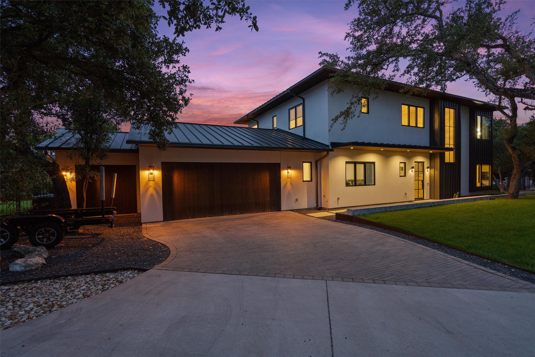 1500 The High Road Austin, TX 78746 - Photo 39 of 40 Modern two-story residence featuring a metal roof, stucco exterior, and dark wood-finish garage doors
