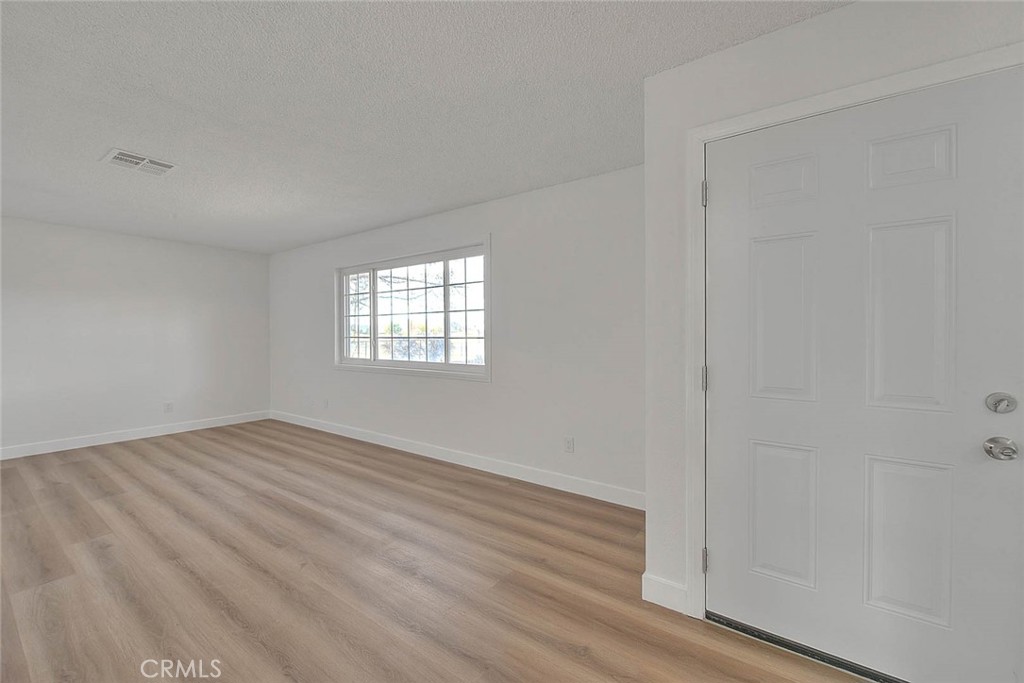 22133 Thunderbird Road Apple Valley, CA 92307 - Photo 8 of 29 a view of an empty room with wooden floor and a window