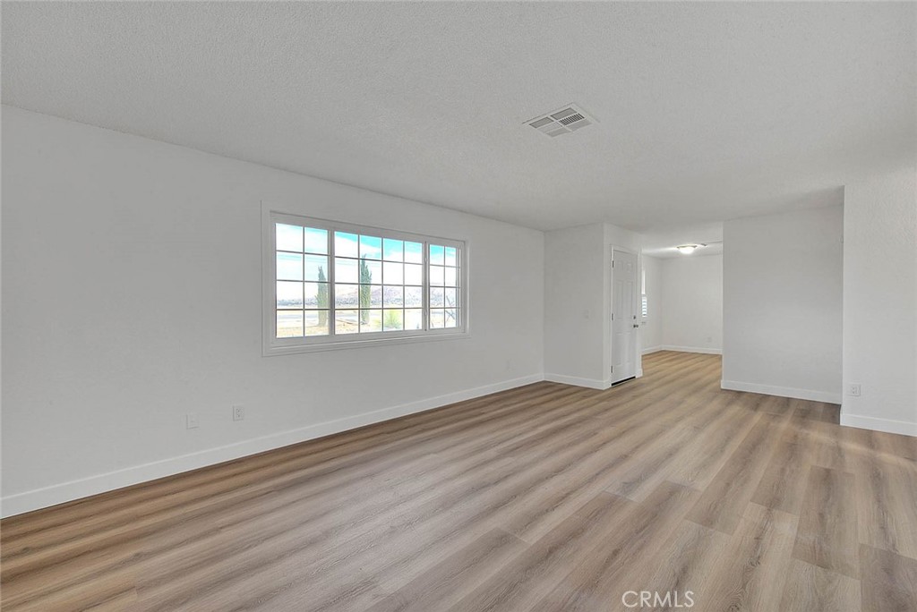 22133 Thunderbird Road Apple Valley, CA 92307 - Photo 9 of 29 a view of empty room with wooden floor and fan