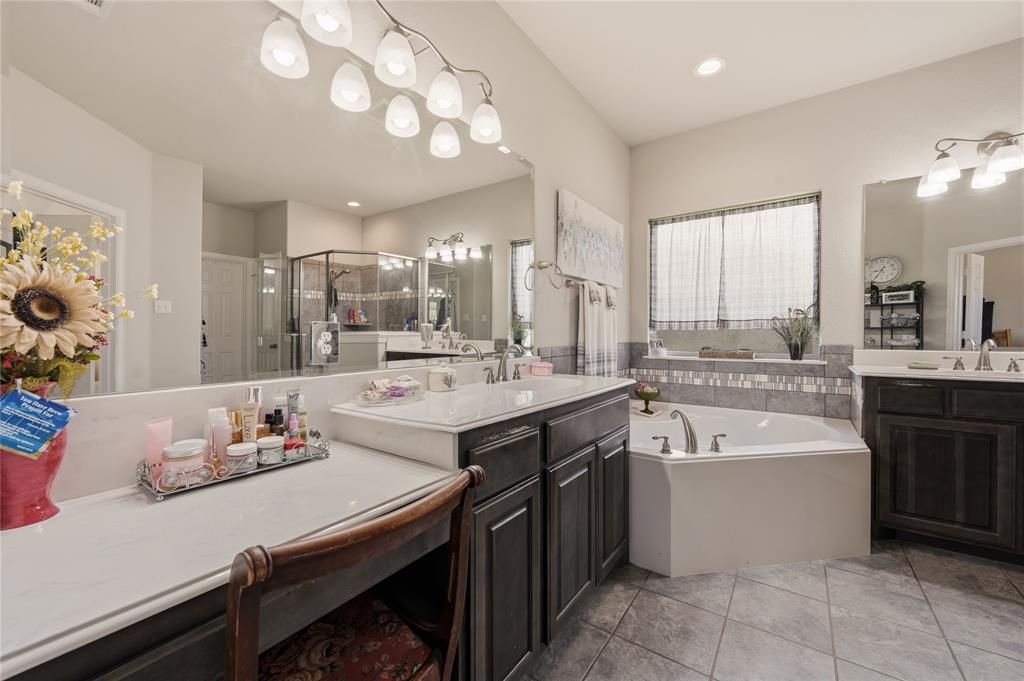 140 Chestnut Road Waxahachie, TX 75165 - Photo 19 of 26 Spacious bathroom featuring a built-in corner soaking tub, dual vanities with undermount sinks, a dedicated vanity seating area, and tile flooring