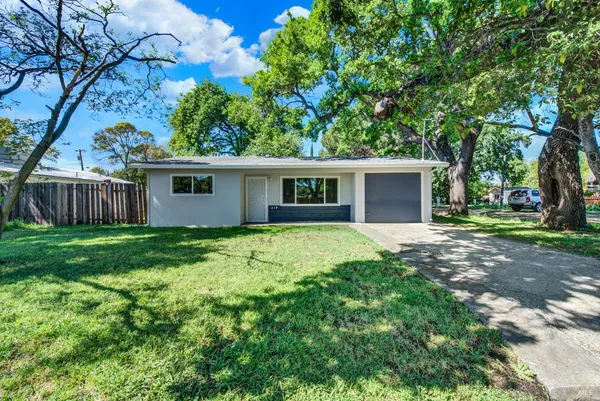 a view of a house with a yard and large tree