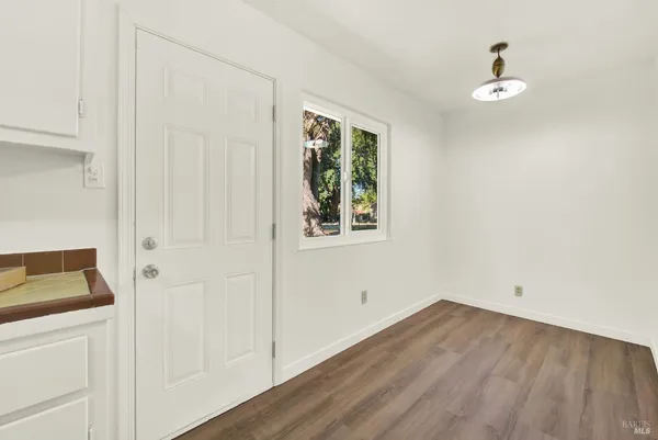 a view of an empty room with wooden floor and closet