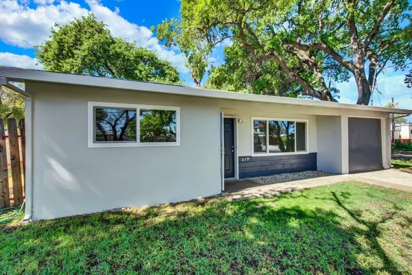 a backyard of a house with large trees and garage