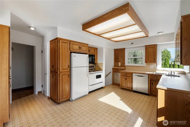 a kitchen with stainless steel appliances a refrigerator a sink a oven and white cabinets