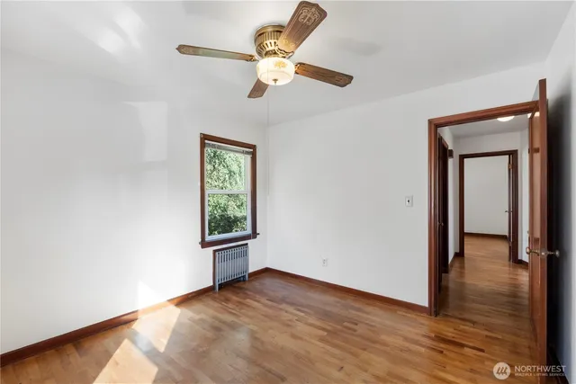 an empty room with wooden floor chandelier fan and windows