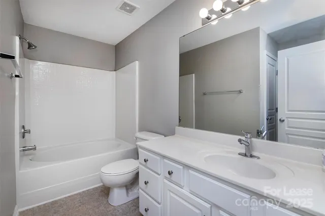 a bathroom with a granite countertop sink a toilet and shower