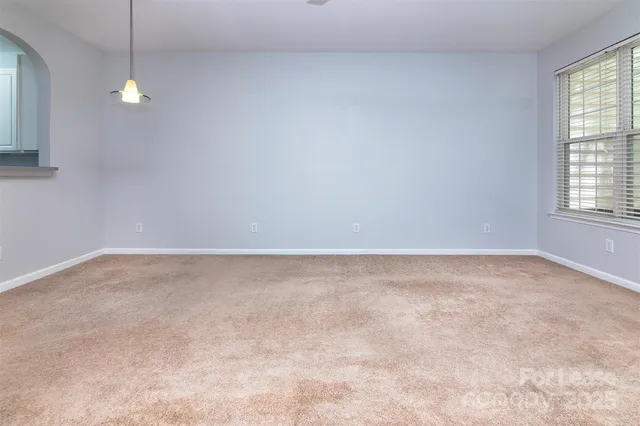an empty room with windows and chandelier fan