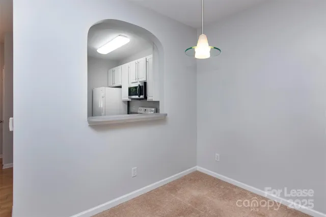 a view of a room with a hanging light and kitchen
