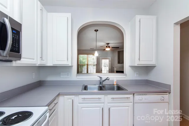 a kitchen with stainless steel appliances granite countertop a sink a stove and white cabinets with wooden floor