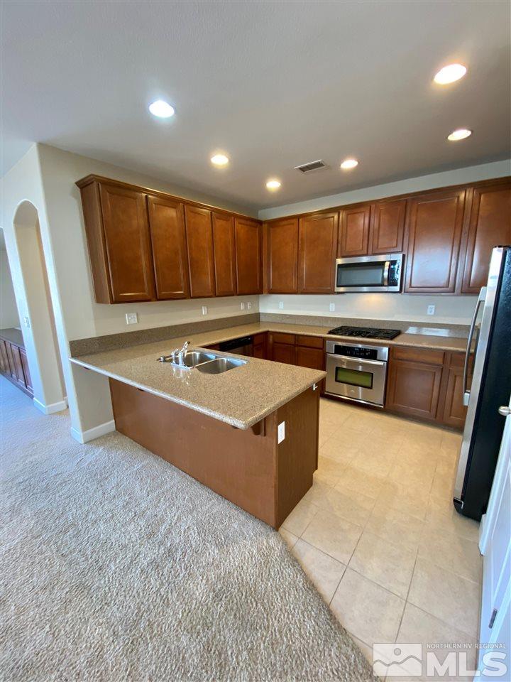 445 Pesaro Way Reno, NV 89521 - Photo 3 of 24 a kitchen with stainless steel appliances granite countertop a stove top oven a sink and a refrigerator