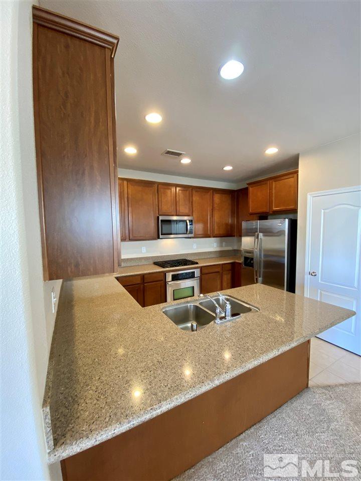 445 Pesaro Way Reno, NV 89521 - Photo 4 of 24 a large kitchen with stainless steel appliances granite countertop a large counter top and a refrigerator