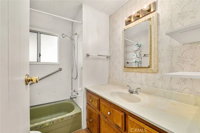 a bathroom with a sink a mirror a bathtub and shower