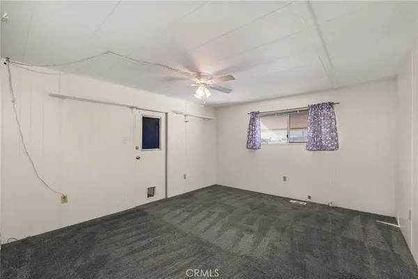 an empty room with windows and fan