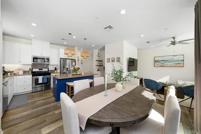 a living room with stainless steel appliances furniture a dining table and kitchen view