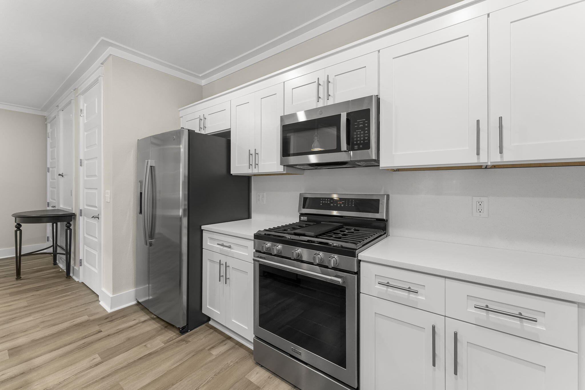 725 J D Miller Road, Unit 106 Santa Rosa Beach, FL 32459 - Photo 6 of 19 a kitchen with stainless steel appliances white cabinets and a stove a microwave oven with wooden floor