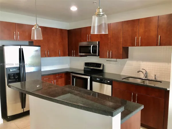 a kitchen with stainless steel appliances granite countertop a sink a stove and a refrigerator