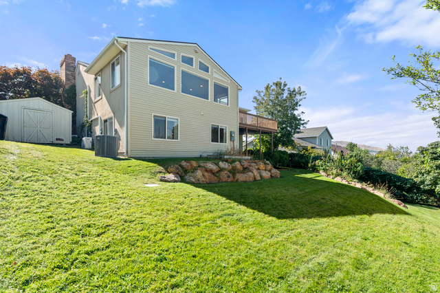 11934 South Cedar Ridge Road Sandy, UT 84094 - Photo 42 of 58 Expansive sloped lawn with a rock retaining wall and a storage shed
